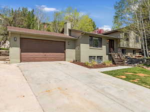 View of front facade with a chimney, brick siding, an attached garage, and concrete driveway