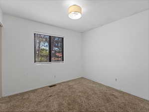 Carpeted empty room with visible vents and baseboards