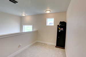 Empty room featuring light colored carpet, visible vents, and baseboards