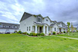 View of front of house with covered porch, stucco siding, a residential view, stone siding, and a front lawn