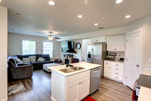 Kitchen featuring wood finished floors, a sink, open floor plan, visible vents, and appliances with stainless steel finishes