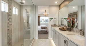 Ensuite bathroom at primary bedroom with a tile shower, tile patterned floors, double vanity, and two sinks