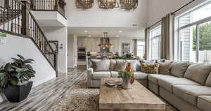 Living room featuring wood finished floors, a high ceiling, stairway, a chandelier, and recessed lighting