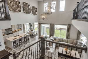 Living area featuring a notable chandelier, a towering ceiling, and wood finished floors