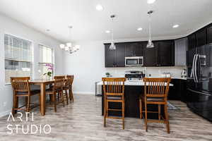 Kitchen with an inviting chandelier, baseboards, light countertops, appliances with stainless steel finishes, and recessed lighting