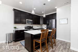Kitchen featuring stainless steel appliances, visible vents, a sink, light countertops, and tasteful backsplash