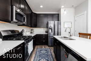 Kitchen with stainless steel appliances, visible vents, a sink, light countertops, and light wood-type flooring
