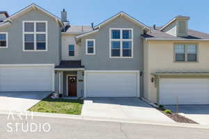Townhome / multi-family property with concrete driveway, stucco siding, a shingled roof, and an attached garage