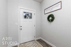 Doorway with baseboards and wood finished floors