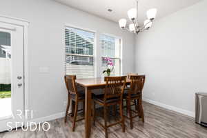 Dining space featuring baseboards, a chandelier, visible vents, and wood finished floors