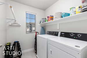 Washroom with washing machine and clothes dryer, laundry area, baseboards, and light tile patterned floors