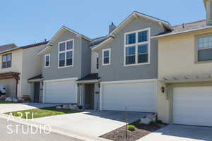 Multi unit property featuring an attached garage, concrete driveway, stucco siding, and a chimney