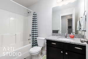 Bathroom with toilet, shower / tub combo with curtain, and vanity