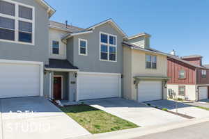 View of property with an attached garage, stucco siding, a shingled roof, and driveway