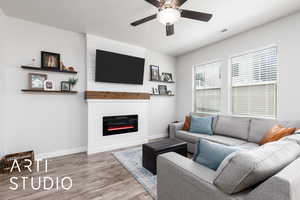 Living area with a fireplace, baseboards, a ceiling fan, and wood finished floors