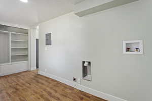 Washroom featuring wood finished floors, baseboards, a textured ceiling, electric panel, and washer hookup