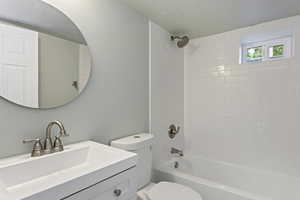 Full bath featuring vanity, a textured ceiling, shower / bathing tub combination, and toilet