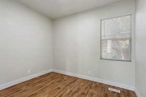 Empty room featuring visible vents, light wood-style flooring, and baseboards