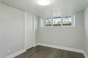 Empty room featuring baseboards, dark wood-style flooring, and a textured ceiling
