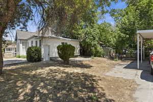 View of yard featuring fence, a carport, and driveway