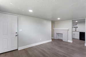 Unfurnished living room with baseboards, a sink, a textured ceiling, and wood finished floors