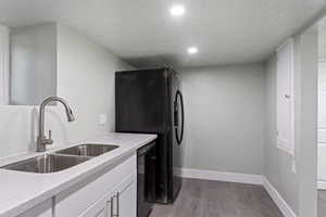 Kitchen with a sink, baseboards, black appliances, and wood finished floors