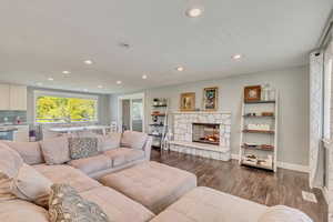 Living area with a fireplace, dark wood finished floors, visible vents, baseboards, and recessed lighting