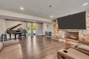 Living area with wood finished floors, a textured ceiling, recessed lighting, a fireplace, and baseboards