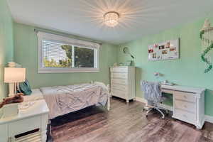 Bedroom featuring dark wood-style flooring and baseboards