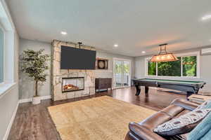 Game room featuring a fireplace, pool table, dark wood-style flooring, an AC wall unit, and recessed lighting