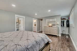 Bedroom featuring recessed lighting, connected bathroom, baseboards, and dark wood-style floors