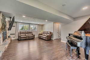 Living room featuring stairway, a fireplace, baseboards, and wood finished floors