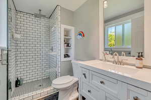 Bathroom featuring toilet, vanity, and a shower stall
