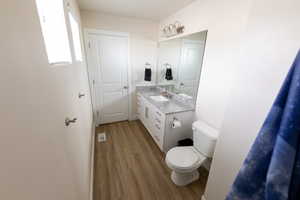 Bathroom with toilet, visible vents, wood finished floors, and vanity