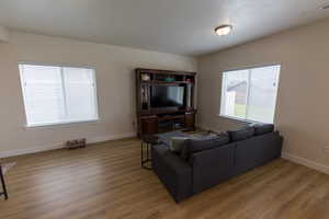Living room with baseboards, visible vents, and wood finished floors