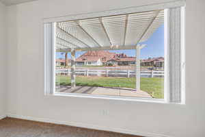 Carpeted spare room featuring plenty of natural light, a residential view, and baseboards
