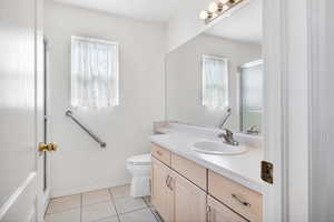 Full bath with toilet, a shower with door, baseboards, tile patterned flooring, and vanity