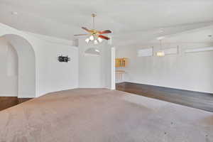 Unfurnished room featuring ceiling fan, carpet flooring, and arched walkways
