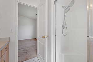 Full bath with tile patterned floors, vanity, and a tile shower