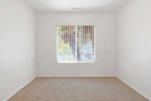 Carpeted empty room with visible vents, baseboards, and a healthy amount of sunlight