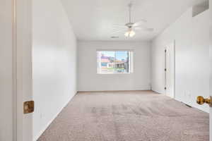 Empty room with light carpet, baseboards, a ceiling fan, and visible vents