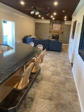 Dining space with a fireplace, stone tile floors, ornamental molding, and baseboards