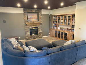 Living area with baseboards, a stone fireplace, crown molding, and recessed lighting