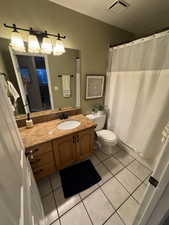 Full bathroom featuring toilet, tile patterned floors, vanity, and visible vents