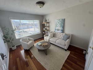 Living area featuring a textured ceiling, baseboards, and wood finished floors