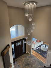 Foyer entrance featuring an inviting chandelier, baseboards, and stone finish floor