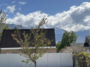 View of side of home featuring fence, a shingled roof, and a mountain view