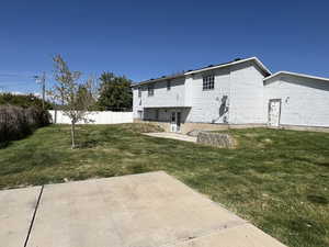 Back of property featuring a yard, a patio, and fence