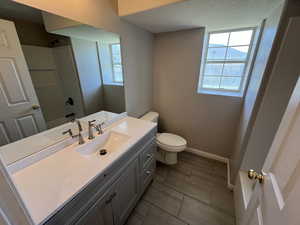 Bathroom with toilet, baseboards, walk in shower, tile patterned flooring, and vanity