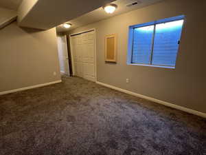 Interior space featuring carpet flooring, visible vents, and baseboards